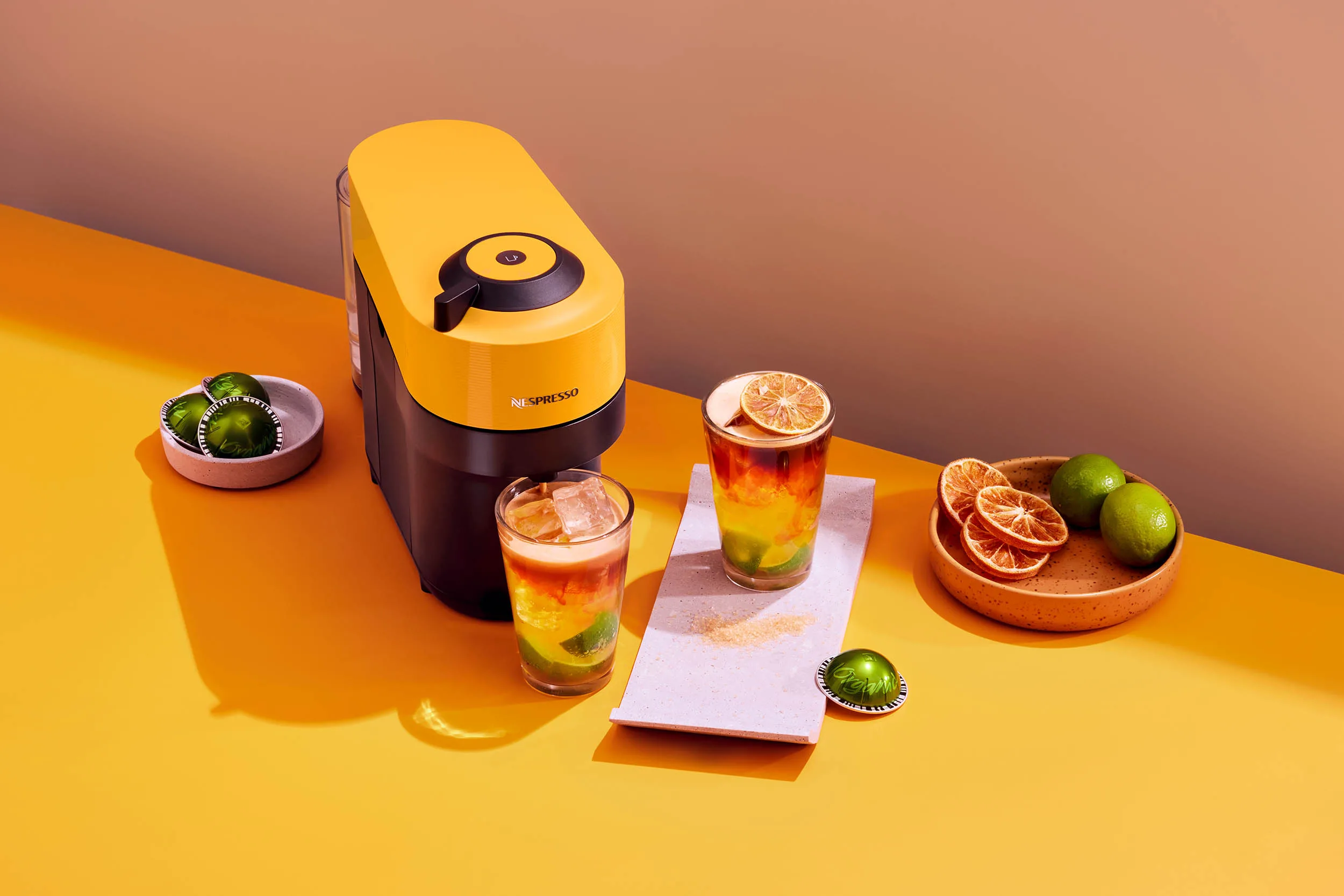 Farbstarke Werbeaufnahme der Vertuo Pop Yellow mit kreativem Kaffeerezept und Setdesign in gelben Farbtönen.