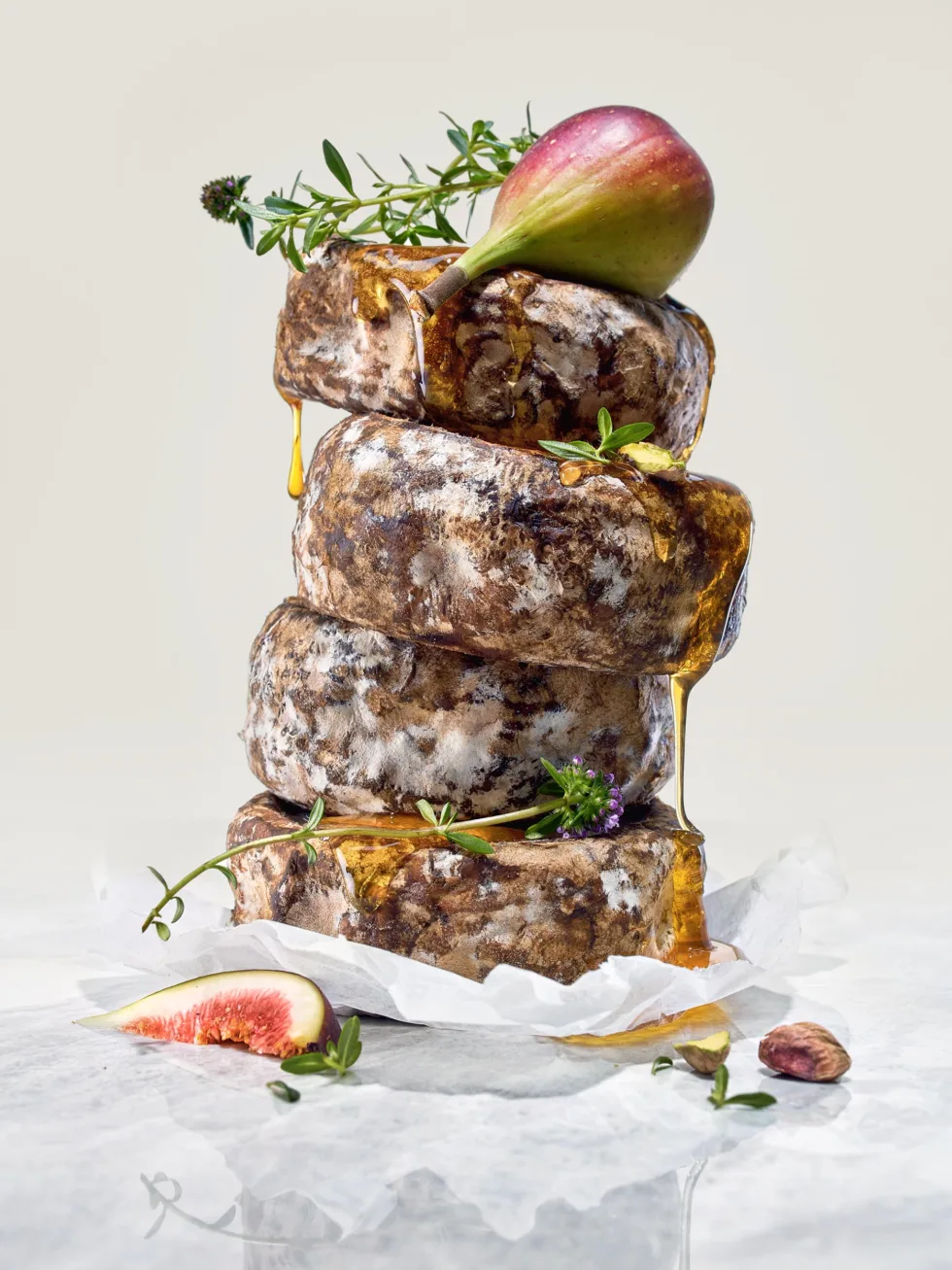 Stillleben mit französischem Rohmilchkaese Tomme de Savoie, Kräutern, Feigen und Honig